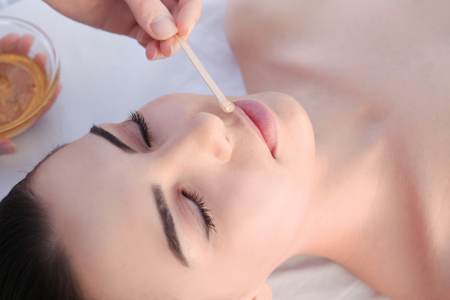 Depilating Young Woman's Face with Wax in Spa Center
