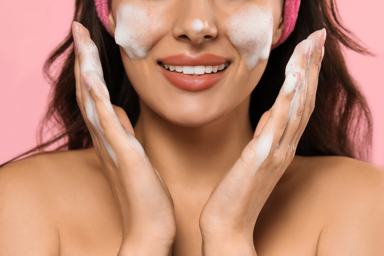 Beautiful Woman Applying Facial Cleansing Foam on Pink Backgroun