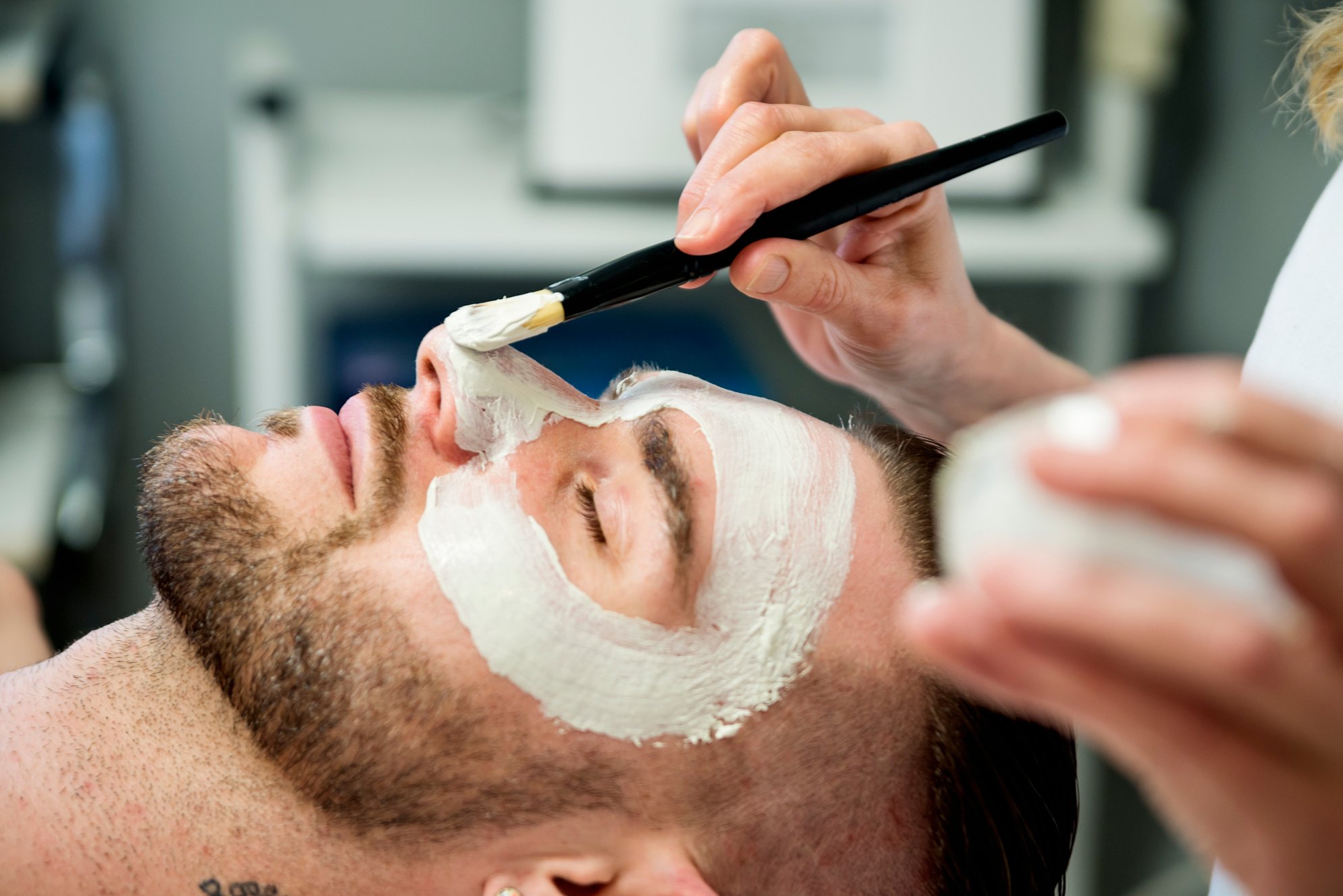 Young man receiving a facial treatment in beauty spa.